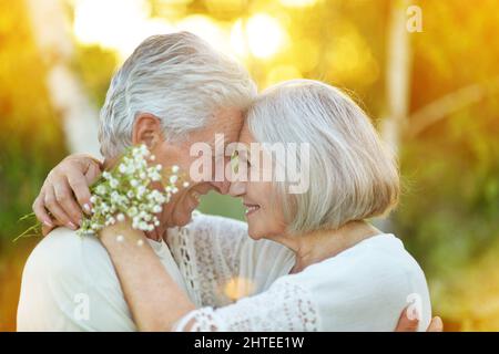 Felice coppia senior che abbraccia il parco estivo Foto Stock