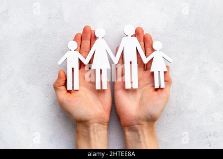 Mani che tengono figure in legno di famiglia. Concetto di cura e protezione Foto Stock