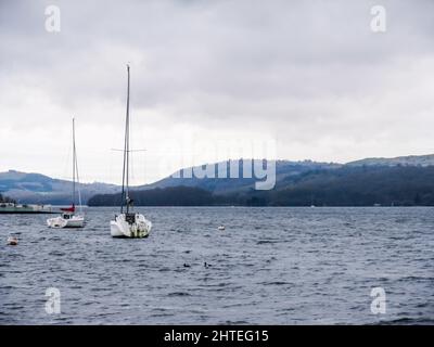 Due barche a vela ormeggiate sul lago Windermere nel Lake District, Regno Unito, in una giornata fredda e piovosa Foto Stock