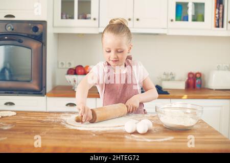 Può cuocere tutto da solo. Adorabile bambina che cucinava a casa in cucina. Foto Stock