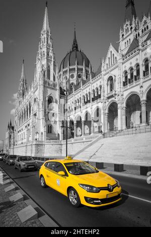 Foto a colori verticali selettive di un taxi Renault vicino all'edificio del parlamento ungherese a Budapest Foto Stock