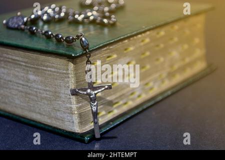 La croce sopra la bibbia su tavola di legno con luce della finestra, tono vintage. Foto Stock