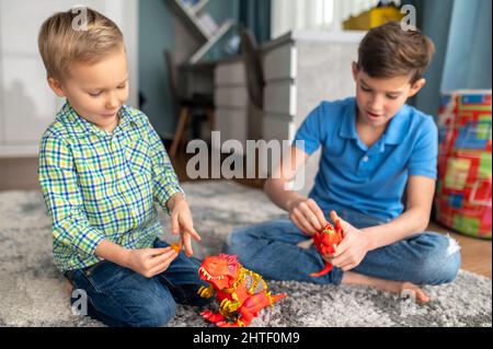 Due bambini si concentrarono sui loro dinosauri giocattolo Foto Stock