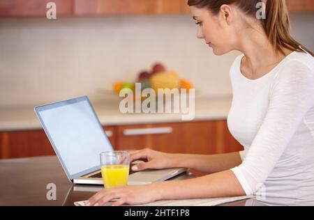 Recuperare gli eventi attuali. Scatto corto di una giovane donna attraente usando il suo laptop mentre si rilassa a casa. Foto Stock