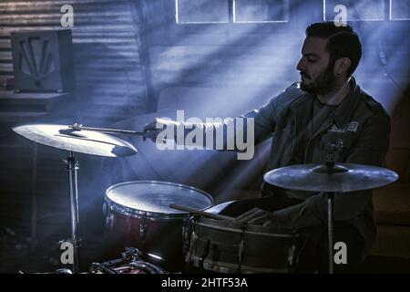 Un batterista suona il suo Kit in una Smoky Room Foto Stock