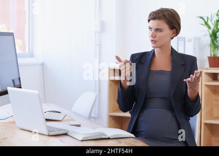 Calcolando il suo budget del bambino. Una donna d'affari incinta che conta sulle sue mani mentre si siede alla sua scrivania d'ufficio. Foto Stock