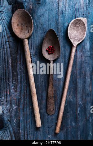 vecchi cucchiai di legno con grani di pepe su un rustico sfondo di legno Foto Stock