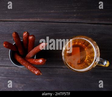 Salsicce con birra su sfondo di legno scuro Foto Stock