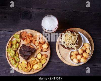 Spuntini alla birra su un tavolo di legno. Birra con pretzel e vari spuntini. Foto Stock