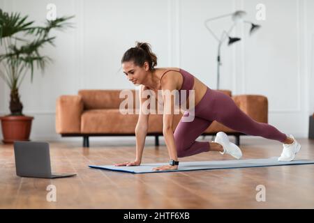 Giovane donna allegra facendo Cross Body Mountain Climbers esercizio Foto Stock