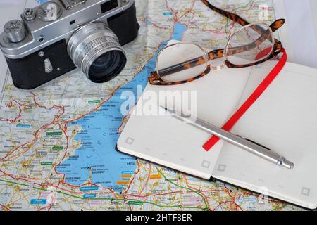 Febbraio 2022 - Pianificazione del viaggio - macchina fotografica vecchia, con libro di note, occhiali e una mappa del Lago di Garda in Italia Foto Stock