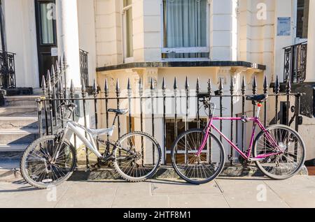 Biciclette lasciate contro ringhiere di ferro su una strada a Londra, Regno Unito Foto Stock