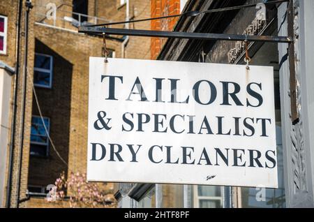 Un cartello appeso all'esterno di un negozio di sarti e lavasciuga in Earl's Court, Londra Foto Stock