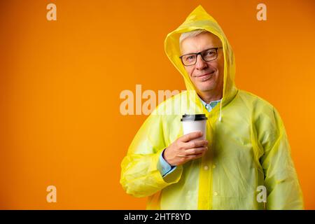 Uomo maturo che indossa il impermeabile su sfondo giallo Foto Stock