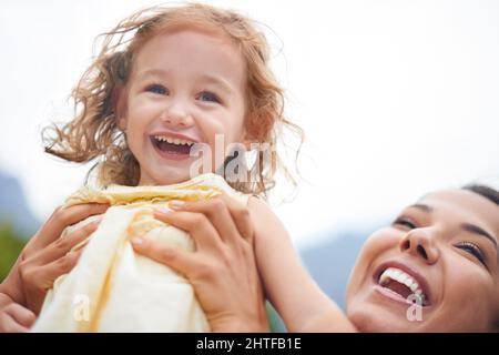 La vita è un'avventura. Scatto corto di una madre gioiosa che solleva la figlia al cielo. Foto Stock