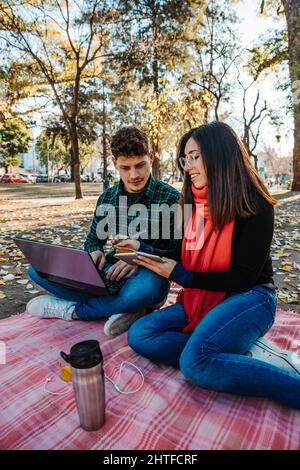 giovane coppia che usa un computer portatile per lavorare all'aperto Foto Stock