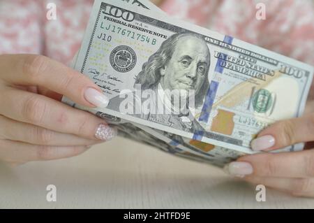 Le mani delle donne tengono i dollari in contanti. 1000 dollari in 100 banconote primo piano. Crisi finanziaria. Foto Stock