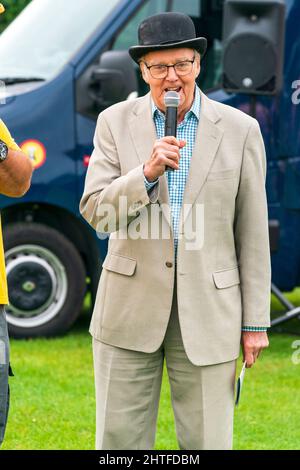 Mike Fitzgerald. Uomo anziano in piedi all'esterno, rivolto verso il telespettatore, contatto visivo, vestito in abito grigio a due pezzi e bowler tatty e parlando nel microfono Foto Stock