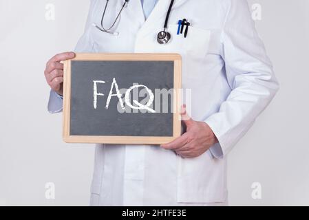 Lavagna con ''FAQ'' scritta su di essa nelle mani di un medico su sfondo bianco Foto Stock