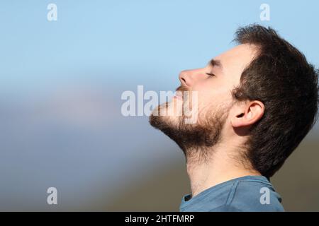 Vista laterale primo piano ritratto di un uomo soddisfatto rilassante respirare aria fresca all'aperto Foto Stock