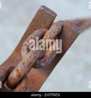 Una catena è solo forte come la maglia più debole.... Primo piano di una catena di cavi arrugginita. Foto Stock