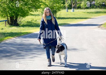 Bella giovane donna che cammina un cane in un parco Foto Stock