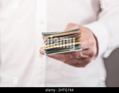 Uomo d'affari mano primo piano che tiene US dollari stack. Concetto di finanza ed economia. Uomo che riceve o dà valuta. Foto di alta qualità Foto Stock
