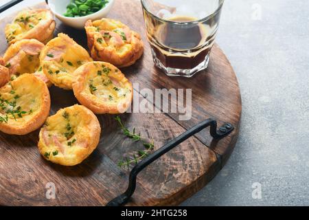 Deliziosi muffin alle uova con cipolle verdi, pancetta, formaggio e pomodori su tavola di legno su sfondo chiaro. Sana alta proteina e bassa colazione carb. Foto Stock