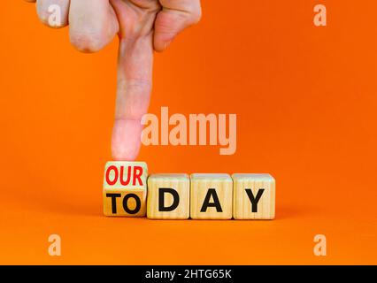 Oggi è il nostro simbolo del giorno. L'uomo d'affari trasforma il cubo di legno e cambia le parole di concetto oggi al nostro giorno. Bellissimo sfondo arancione, spazio copia. Autobus Foto Stock