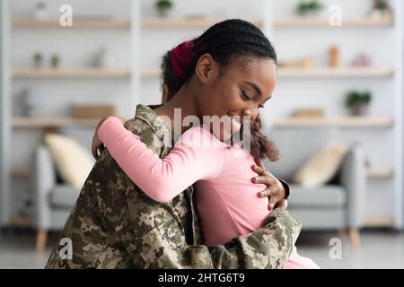 Vista laterale del soldato della madre nera che abbraccia l'hcer hild Foto Stock