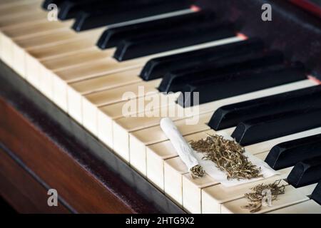 Messa a fuoco selettiva di una sigaretta arrotolante su un pianoforte Foto Stock