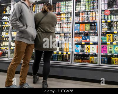 Kirkland, WA USA - circa Febbraio 2022: Un uomo caucasico e una donna asiatica che acquista birra nella sezione alcol di un intero mercato alimentare. Foto Stock