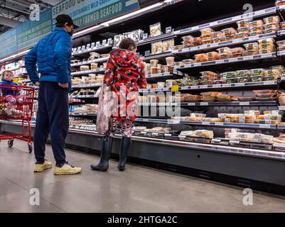 Kirkland, WA USA - circa Febbraio 2022: Vista di un uomo e una donna con il loro bambino, shopping al corridoio di cibo preparato all'interno di un intero mercato di cibi Foto Stock