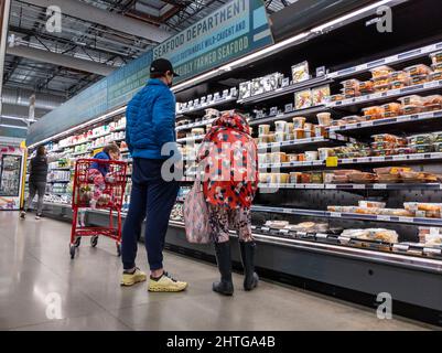 Kirkland, WA USA - circa Febbraio 2022: Vista di un uomo e una donna con il loro bambino, shopping al corridoio di cibo preparato all'interno di un intero mercato di cibi. Foto Stock