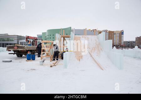 Costruttori in giacche blu con cappe sul montaggio di uno scivolo di legno Foto Stock