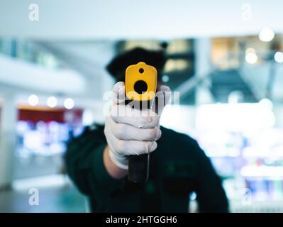 Primo piano di un uomo che punta un termometro a pistola alla fotocamera Foto Stock