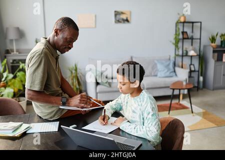 Ritratto di padre africano americano aiutare ragazza adolescente studiare a casa in verde interno, spazio copia Foto Stock