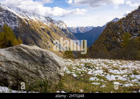 Valle alpina in autunno dopo una piccola nevicata con rocce in primo piano. Foto Stock