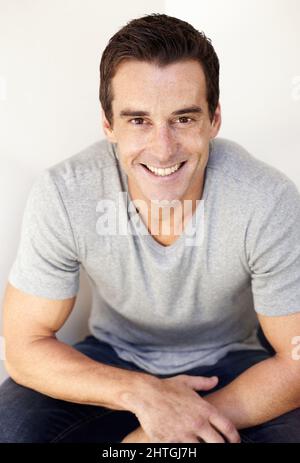 HES casualmente e felice. Ritratto di un bel giovane uomo vestito casualmente e rilassato. Foto Stock