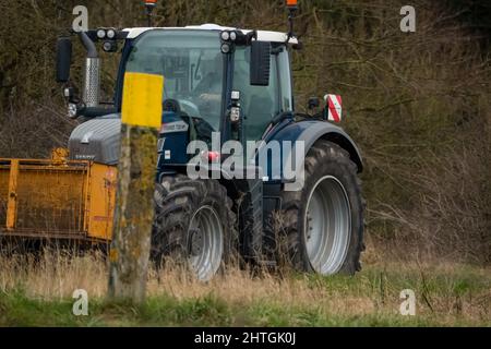 Trattore FENDT 720 dotato di una scatola di trasporto con attacco rapido Twose gialla, che procede lungo una corsia di campagna Foto Stock