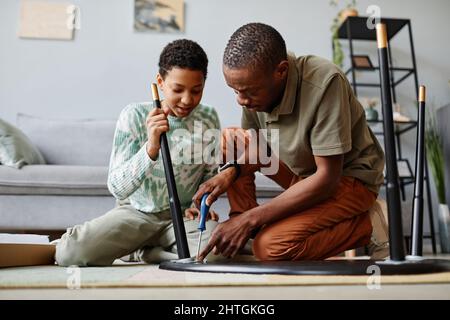 Ritratto di uomo afroamericano che monta i mobili a casa con la figlia aiutare Foto Stock