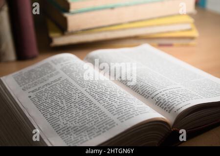 Primo piano di un libro di una bibbia su un tavolo su cui ci sono altri libri Foto Stock