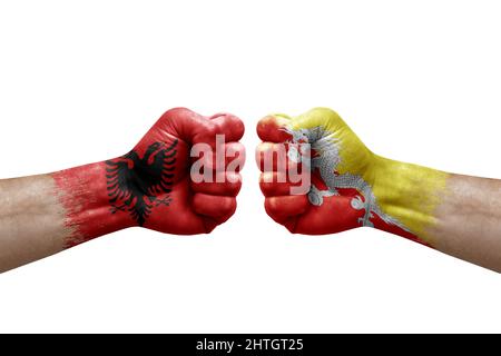Due mani si pugno l'una all'altra su sfondo bianco. Bandiere di paese dipinte pugni, conflitto di crisi concetto tra albania e bhutan Foto Stock