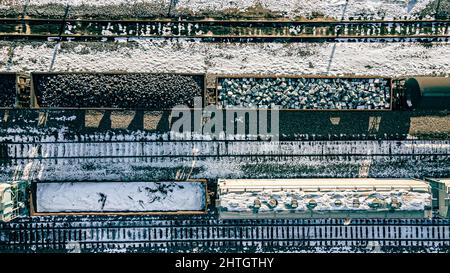 Cantiere coperto di neve durante la stagione invernale con contenitori pieni di risorse. Foto Stock