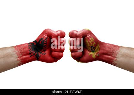 Due mani si pugno l'una all'altra su sfondo bianco. Bandiere di paese dipinte pugni, conflitto di crisi concetto tra albania e montenegro Foto Stock