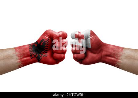 Due mani si pugno l'una all'altra su sfondo bianco. Bandiere di paese dipinte pugni, conflitto concetto di crisi tra albania e tonga Foto Stock