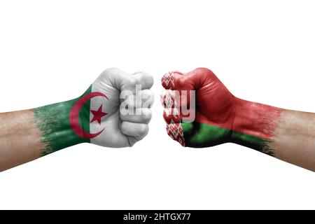 Due mani si pugno l'una all'altra su sfondo bianco. Bandiere di paese dipinte pugni, conflitto di crisi concetto tra algeria e bielorussia Foto Stock