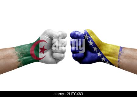 Due mani si pugno l'una all'altra su sfondo bianco. Bandiere di paese dipinte pugni, conflitto di crisi concetto tra algeria e bosnia Foto Stock