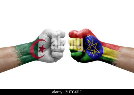 Due mani si pugno l'una all'altra su sfondo bianco. Bandiere di paese dipinte pugni, conflitto concetto di crisi tra algeria ed etiopia Foto Stock