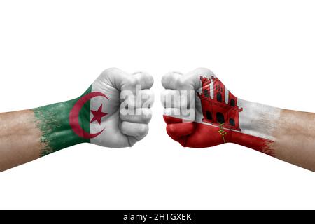 Due mani si pugno l'una all'altra su sfondo bianco. Bandiere di paese dipinte pugni, conflitto di crisi concetto tra algeria e gibilterra Foto Stock